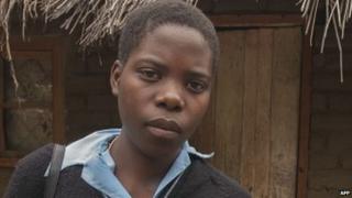 Alinafe Naison,19, wearing a Mponela Community Day Secondary School (MPCDSS) uniform and carrying books, a returnee from underage marriage who has since gone back to school, poses on 7 March 2015 in front of her house at in the village of Kachulu in Malawi