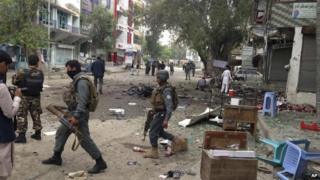 Afghan security forces members inspect the site of a suicide attack near a new Kabul Bank in Jalalabad, east of Kabul, Afghanistan, Saturday, April, 18, 2015.