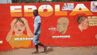 A Liberian man walking pass an ebola awareness painting on a wall in downtown Monrovia, Liberia