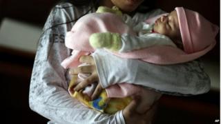 A 13-year-old girl holds her one-month old baby at a shelter for troubled children in Ciudad del Este, Paraguay, on Thursday, May 14, 2015.