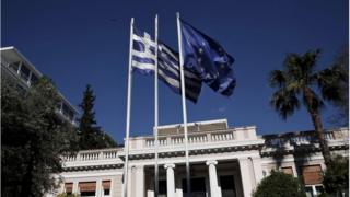A Greek national flag and a European Union flag flutter