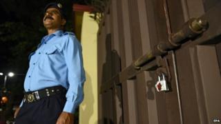 A Pakistani security official stands guard at the Save the Children offices