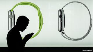 Man using a smartphone in front of an Apple Watch display