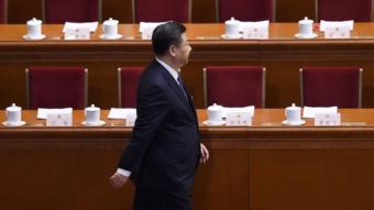 Xi Jinping walking in front of delegates' tables and empty chairs