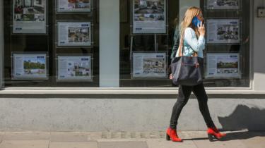 Woman walks past estate agent window