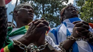 Members of the Africa Diaspora Forum (ADF), civil society organisations, churches, trade unions and other coalitions wear chains and shout slogans during a demonstration against the slave trade and human trafficking in Libya on December 12, 2017 at the Union Buildings in Pretoria.