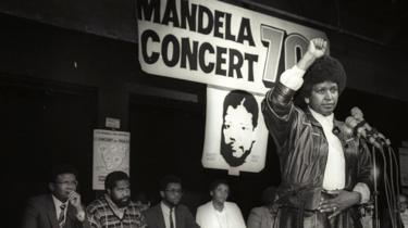 Winnie Mandela raises her fist in a black power salute after announcing that a massive pop concert will be held to mark the 70th birthday of her husband in 1988