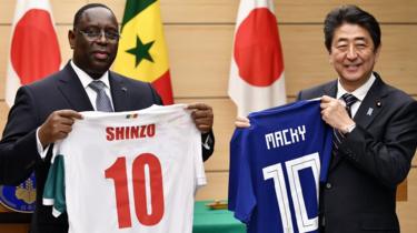 Senegal"s President Macky Sall (L) and Japan"s Prime Minister Shinzo Abe (R) exchange national soccer jerseys at the end of a joint press conference at the Prime Minister"s official residence in Tokyo, Japan, 13 December 2017.