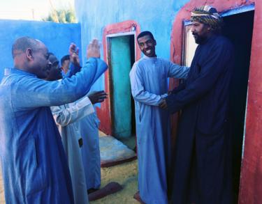 Akram (centre) goes from house to house with friends to invite people to his wedding