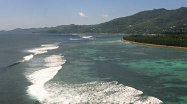 Waves break on the beach of an island in the Seychelles