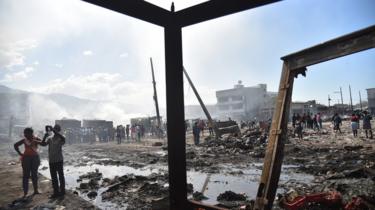 Citizens stand amid the burnt-out wreckage of the Iron Market.