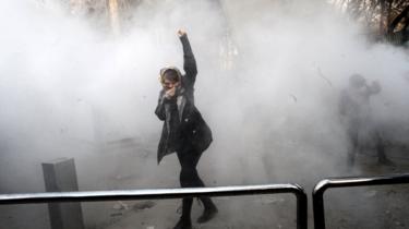 An Iranian university student raises her fist in a cloud of smoke at Tehran University