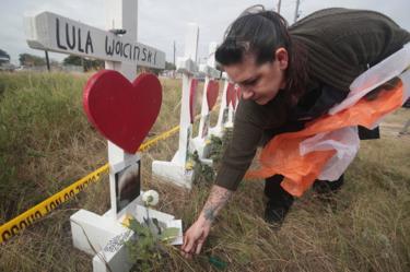 Joyce Mires leaves flowers at a memorial.