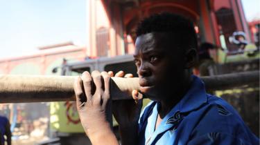 A crying man helps carry a fire hose to tackle the market blaze.