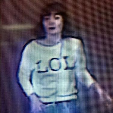 Grainy image shows a woman with brown hair wearing a T-shirt with the letters 