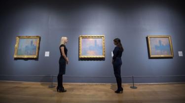 Members of staff look at paintings of the Houses of Parliament by Claude Monet during a photo call for EY Exhibition: Impressionists in London, French Artists in Exile (1870-1904) at the Tate Britain. 30 October 2017.