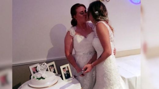 Hannah y su esposa Stacey se besan en el momento de partir el pastel el día de su boda.
