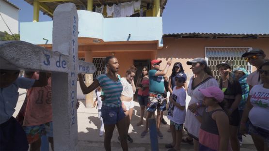 Una joven enseñando una cruz a unos visitantes.