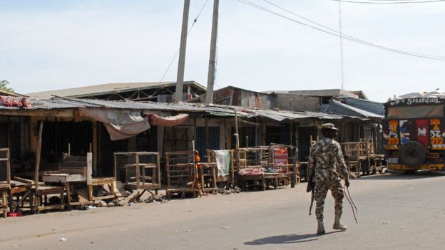 A soldier patrols near the scene of a suicide bomb attack on a market in Maiduguri, after two girls approximately seven or eight years old blew themselves, killing themselves and wounding at least 17 others