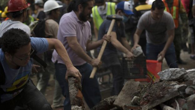 Rescuers and volunteers remove rubble and debris from a flattened building in search of survivors after a powerful quake in Mexico City on September 19, 2017.