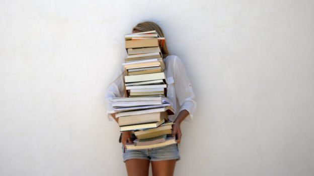 chica sosteniendo pila de libros