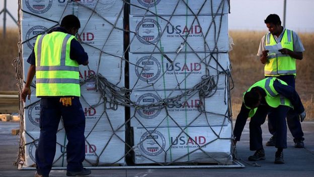 Funcionarios mueven una carga de la USAID en un aeropuerto.