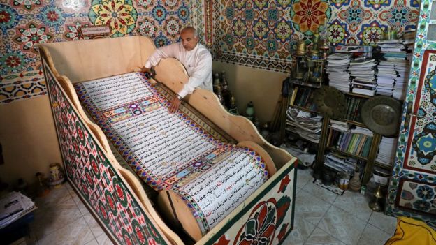 سعد محمد يسحب لفافة المصحف الذي صنعه في بلدة بلقينا شمال القاهرة