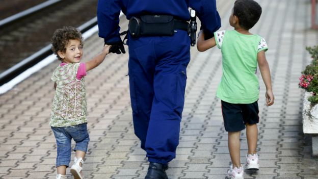 A police officer escorts migrant children along a platform at a railway station in Hegyeshalom, Hungary - 7 September 2015