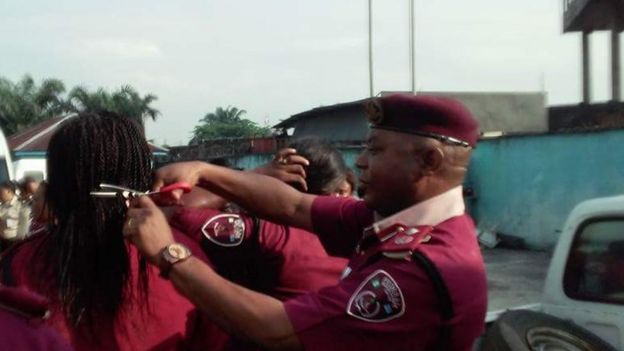 Man in maroon beret cuts a woman's hair in public