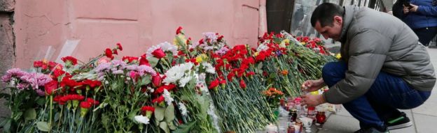 A man lays flowers outside Tekhnologicheskiy Institute metro station to pay tribute to the victims of an explosion in the metro station