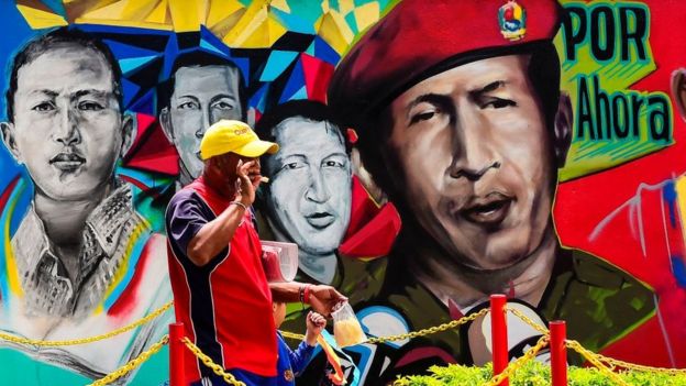 hombre frente a mural de Chávez