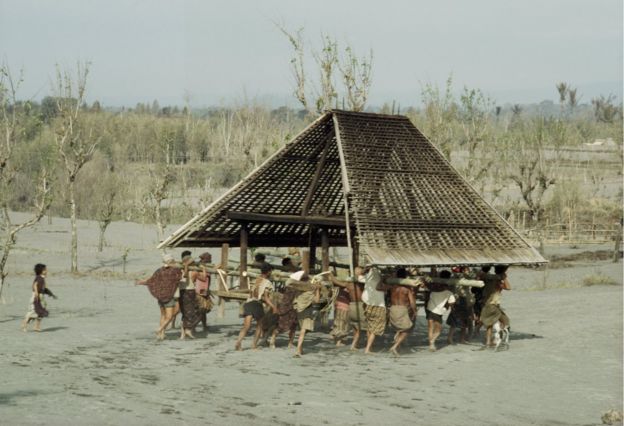 Para petani warga sebuah desa, mengangkut sebuah rumah, untuk memindahkannya ke tempat lebih aman, melintasi abu dan debu yang dimuntahkan Gunung Agung. 