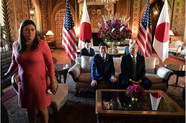 US President Donald Trump greets Japanese Prime Minister Shinzo Abe as he arrives for talks at Trump"s Mar-a-Lago resort in Palm Beach, Florida, on 17 April 2018. White House Press Secretary Sarah Sanders is at left