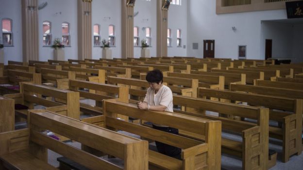 Mulher reza sozinha em uma igreja católica em Tianjin, na China