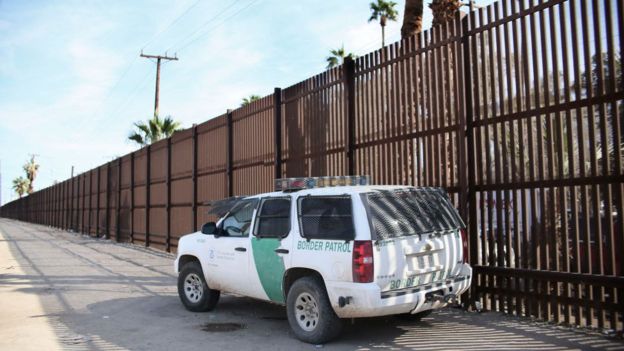 A US Border Patrol truck sits by existing US-Mexico border fencing.