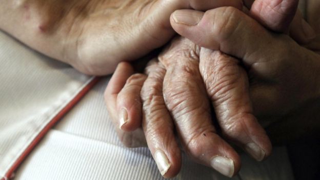 Enfermera sosteniendo las manos de una persona con Alzheimer.