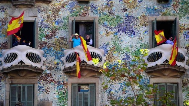 People wave Spanish flags from the Casa Batllo during a pro-unity demonstration in Barcelona on October 29, 2017