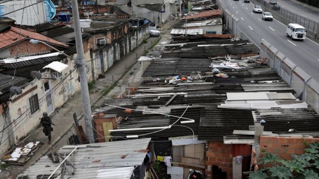 Militar caminha em favela ao lado de avenida