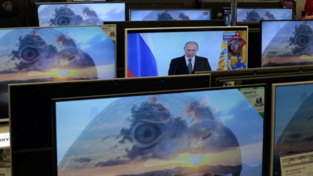Багато телевізорів з різними зображеннями, у тому числі Володимира Путіна