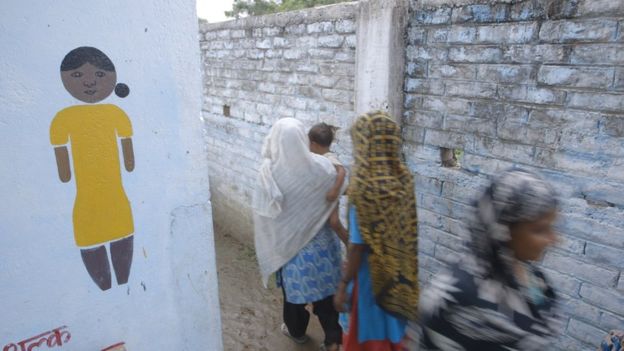 Women walking past a sign into the Shri facility