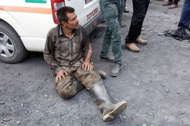 A man sits with his back against a van after the explosion in a coal mine in northern Iran