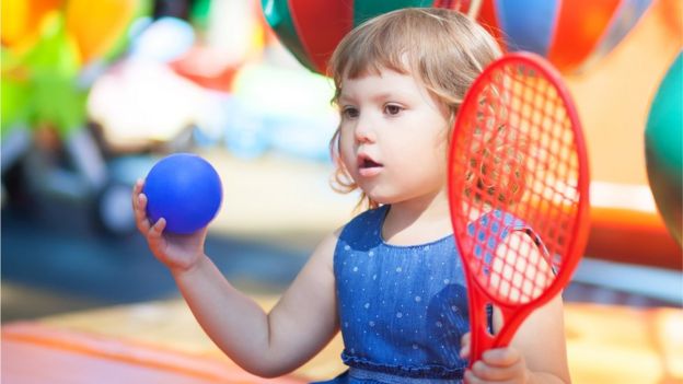 Niña de unos dos años con una raqueta y una pelota