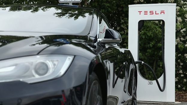 Un auto de Tesla junto a una estación de recarga.