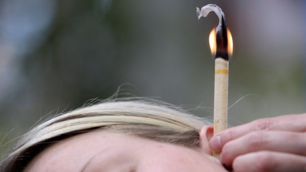 Mujer usando una vela para limpiar el oído