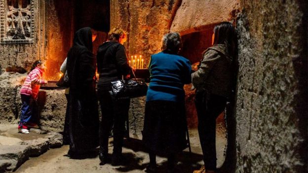 أربعة نساء يقفن أمام الشموع في كهف المصلين