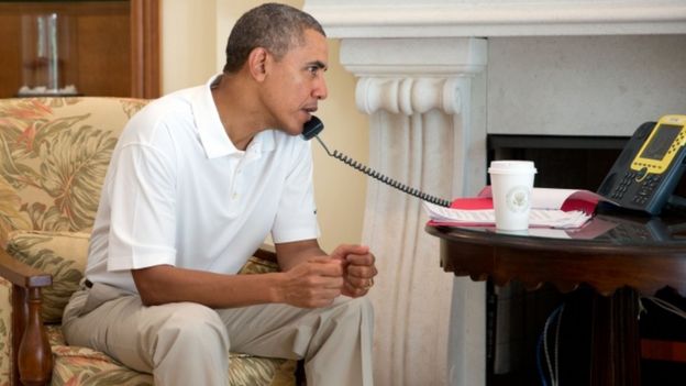 Barack Obama pictured sitting down while on the telephone (file picture)