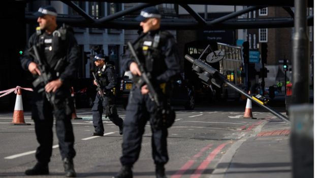 Armed police officers stand near the location where the attacker's van crashed, on London Bridge