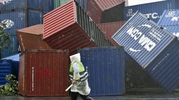 A man walks past downed shipping containers at the Kaohsiung Harbour as typhoon Meranti lashed southern Taiwan on September 14, 2016.