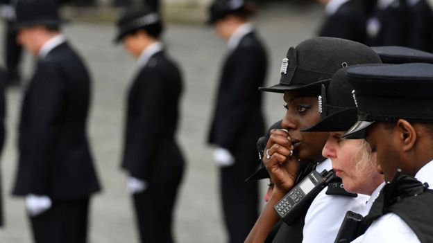 Police officers react as the hearse goes past them