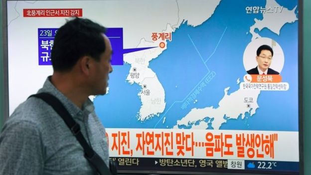 Un hombre camina frente a una pantalla de TV que muestra la posición del sismo en Corea del Norte.